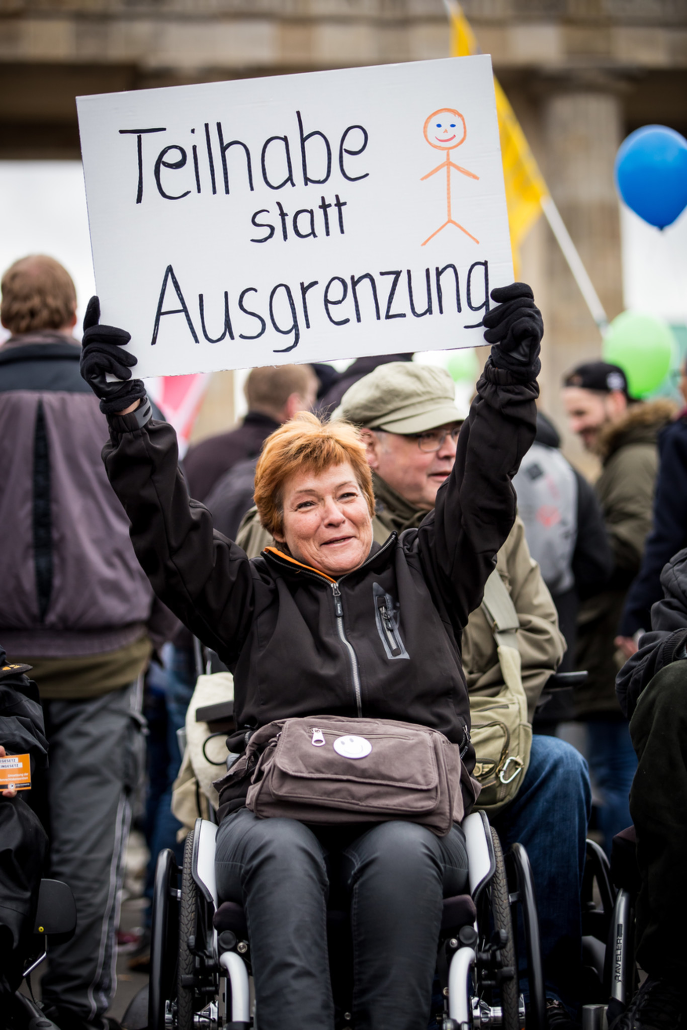 Frau mit Rollstuhl protestiert und hält Banner: Teilhabe statt Ausgrenzung
